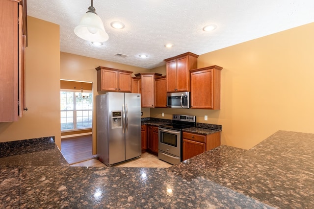 kitchen with pendant lighting, recessed lighting, appliances with stainless steel finishes, brown cabinetry, and a textured ceiling