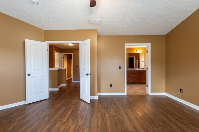 unfurnished bedroom with a textured ceiling, dark wood-type flooring, and baseboards