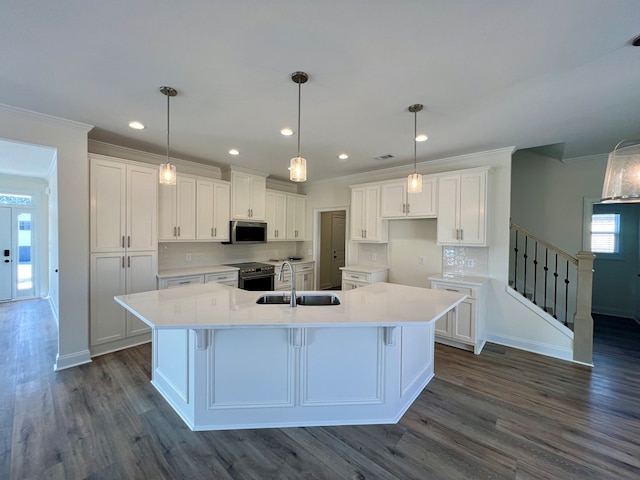 kitchen featuring appliances with stainless steel finishes, pendant lighting, sink, white cabinets, and a spacious island