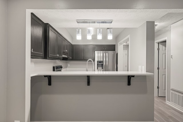 6344 Olde Towne Dr, Columbus, GA 31907 - kitchen featuring stainless steel refrigerator with ice dispenser, a kitchen breakfast bar, light wood finished floors, a peninsula, and decorative light fixtures