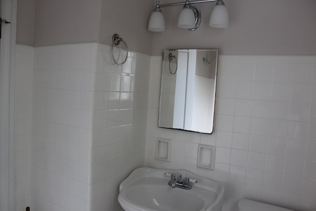 bathroom featuring toilet, a sink, and tile walls