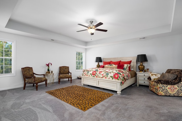 carpeted bedroom with ceiling fan and a raised ceiling