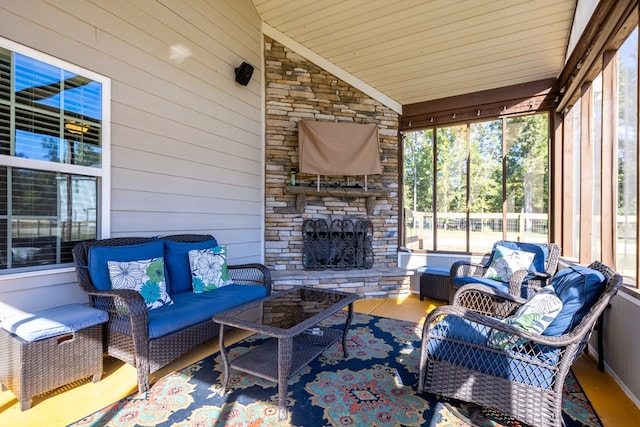 sunroom with an outdoor stone fireplace and lofted ceiling