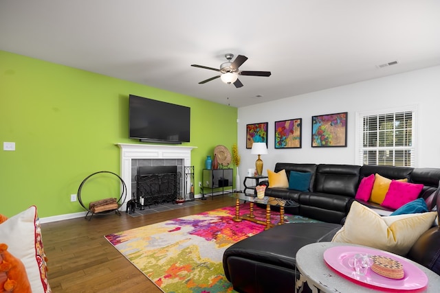 living room featuring ceiling fan, dark hardwood / wood-style flooring, and a tile fireplace