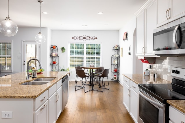 kitchen featuring white cabinets, sink, an island with sink, and appliances with stainless steel finishes