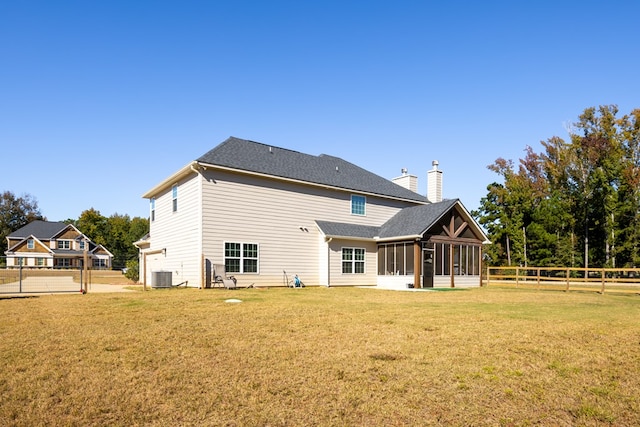 back of property with central air condition unit, a lawn, and a sunroom