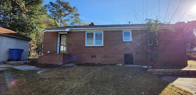 rear view of property with crawl space, brick siding, and a yard