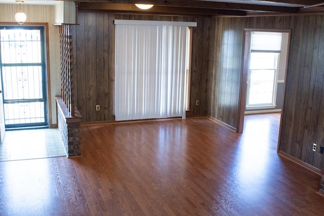 empty room with wood-type flooring, wooden walls, and a healthy amount of sunlight