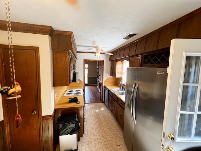 kitchen with sink, wooden walls, ceiling fan, ornamental molding, and appliances with stainless steel finishes