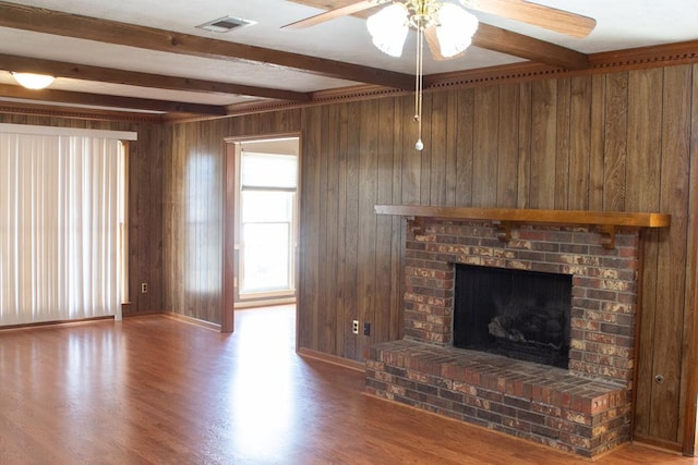 unfurnished living room featuring wooden walls, beamed ceiling, and hardwood / wood-style flooring