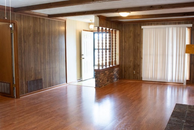 spare room featuring hardwood / wood-style floors, wood walls, and beamed ceiling