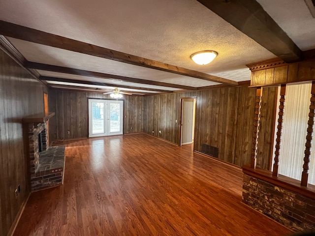 unfurnished living room featuring a textured ceiling, wooden walls, ceiling fan, and dark wood-type flooring