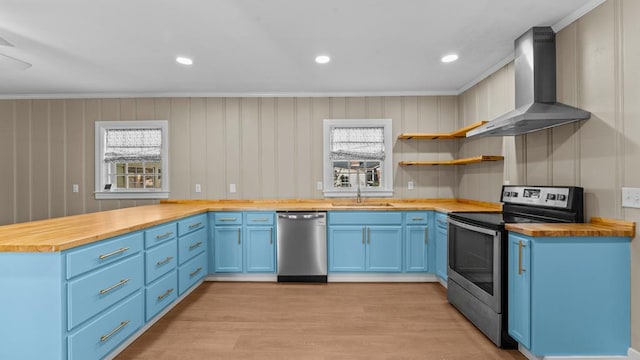 203 Patton Dr, Americus, GA 31719 - kitchen with wall chimney range hood, ornamental molding, blue cabinetry, appliances with stainless steel finishes, and butcher block countertops