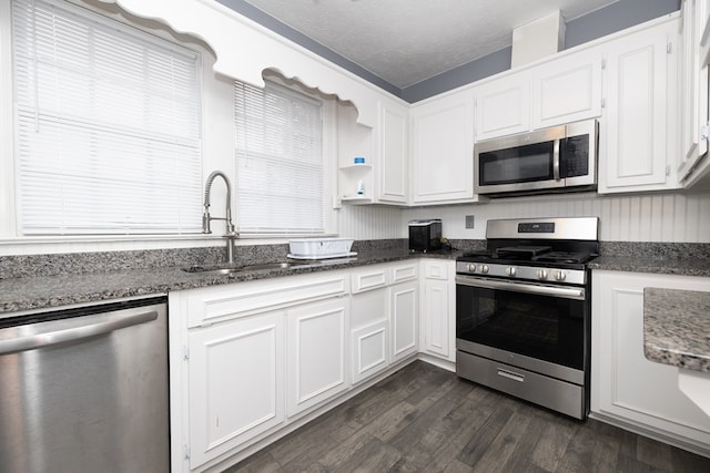 kitchen with appliances with stainless steel finishes, dark hardwood / wood-style flooring, a textured ceiling, sink, and white cabinets