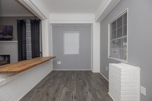 interior space with butcher block countertops, dark hardwood / wood-style floors, crown molding, and a brick fireplace