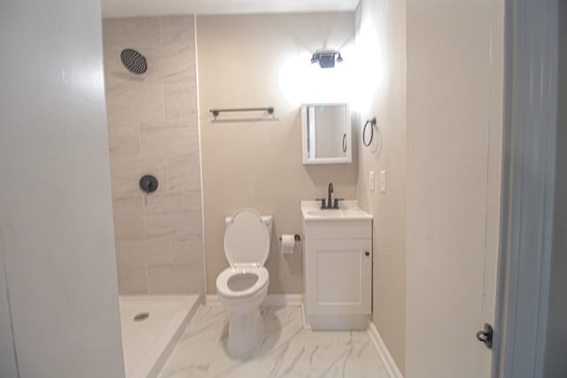 bathroom with tiled shower, vanity, and toilet