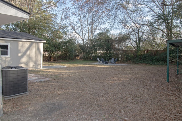 view of yard featuring cooling unit, an outdoor fire pit, and a shed