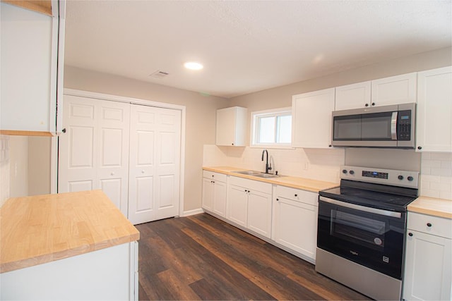 kitchen with dark hardwood / wood-style floors, white cabinetry, sink, backsplash, and stainless steel appliances