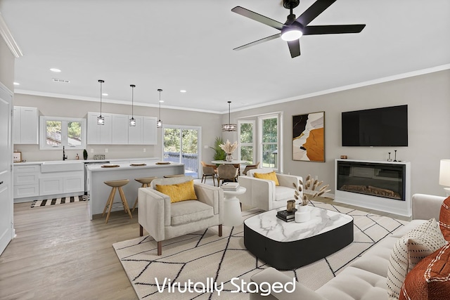 living area featuring light wood-style flooring, ornamental molding, a wealth of natural light, and recessed lighting