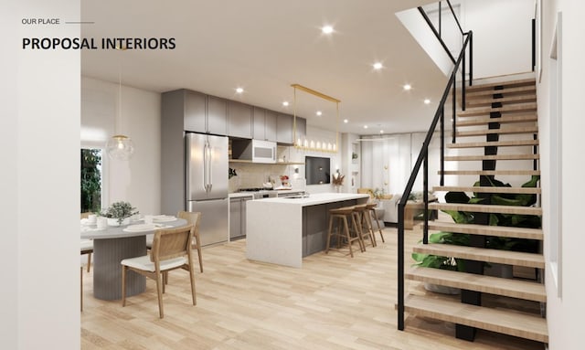 kitchen featuring a center island, decorative light fixtures, light countertops, a kitchen bar, and stainless steel refrigerator