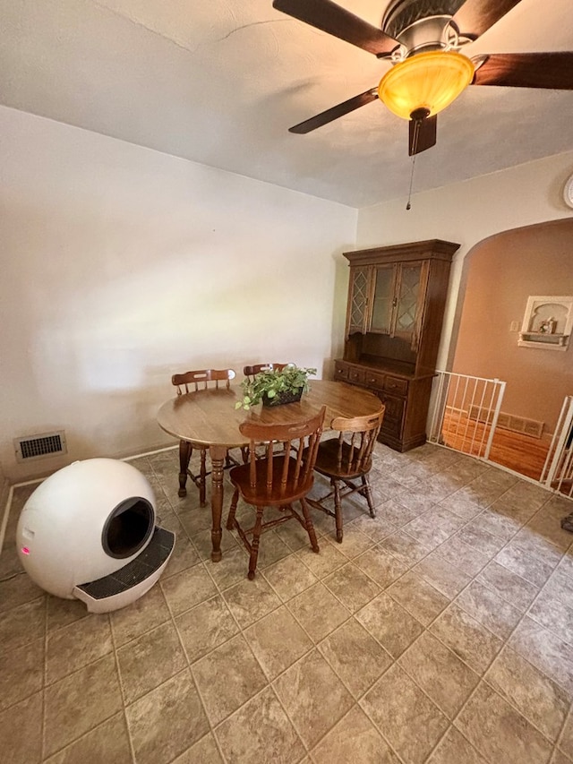 dining room with arched walkways, visible vents, and ceiling fan