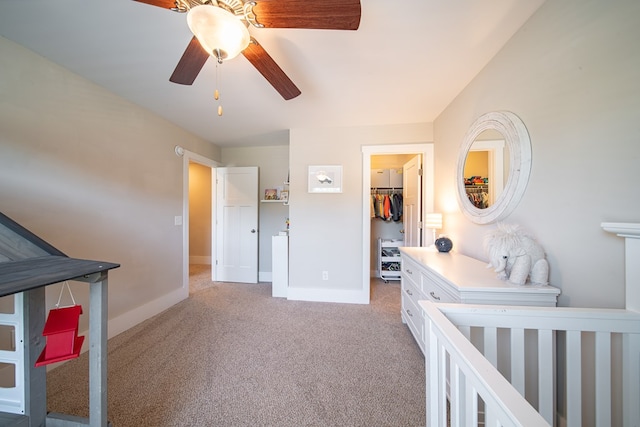 carpeted bedroom featuring ceiling fan, a crib, a spacious closet, and a closet