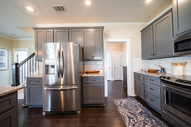 kitchen featuring light stone countertops, ornamental molding, stainless steel appliances, gray cabinets, and dark hardwood / wood-style floors