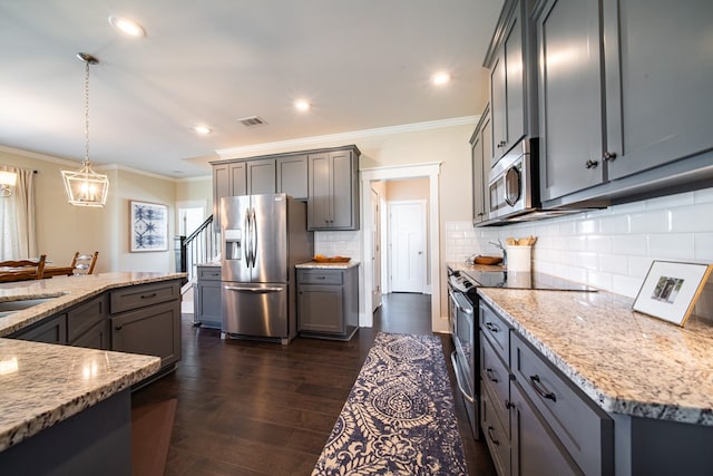 kitchen with light stone countertops, appliances with stainless steel finishes, dark hardwood / wood-style flooring, gray cabinets, and hanging light fixtures