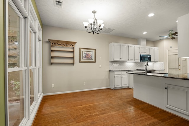 5043 Spyglass Ct, Columbus, GA 31909 - kitchen with stainless steel microwave, backsplash, light wood-style floors, recessed lighting, and a chandelier