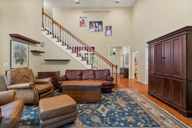 5043 Spyglass Ct, Columbus, GA 31909 - living room featuring stairs, light wood-style floors, a towering ceiling, and baseboards