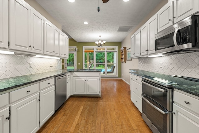 5043 Spyglass Ct, Columbus, GA 31909 - kitchen with stainless steel appliances, a sink, white cabinets, light wood-type flooring, and a peninsula