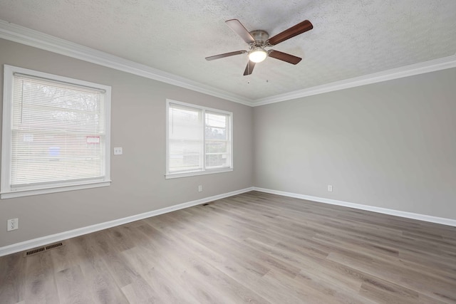 spare room featuring baseboards, wood finished floors, visible vents, and crown molding