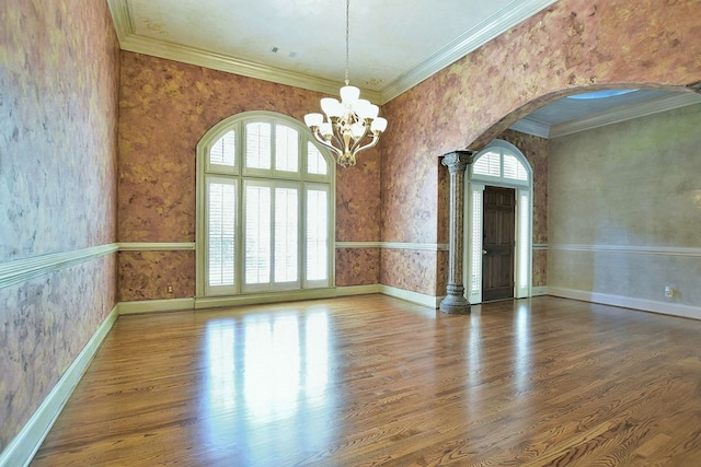 empty room featuring arched walkways, wood finished floors, baseboards, wallpapered walls, and crown molding