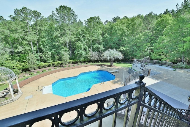 pool with a patio and a view of trees