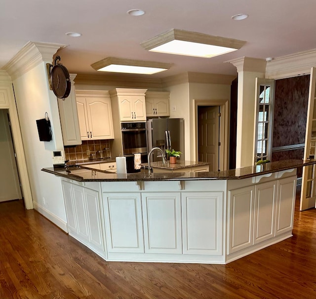 kitchen with stainless steel appliances, dark stone countertops, and dark wood finished floors