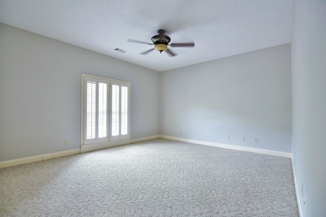 carpeted spare room featuring visible vents, baseboards, and a ceiling fan