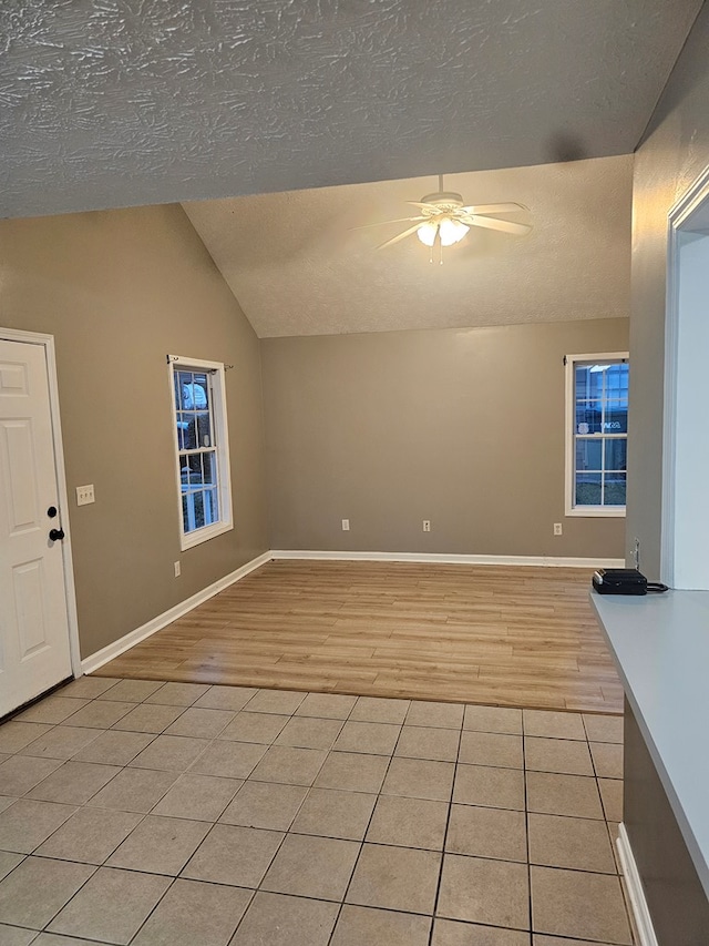 unfurnished living room featuring light tile patterned floors, a textured ceiling, vaulted ceiling, and ceiling fan