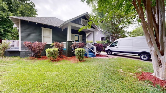 view of front of house featuring a shingled roof, a porch, and a front lawn
