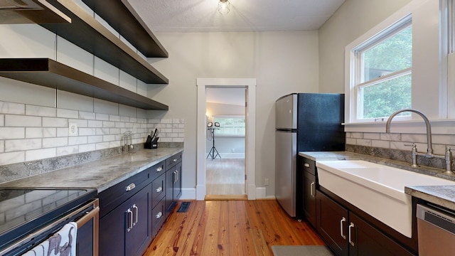 kitchen with stainless steel appliances, open shelves, light wood-style floors, backsplash, and plenty of natural light