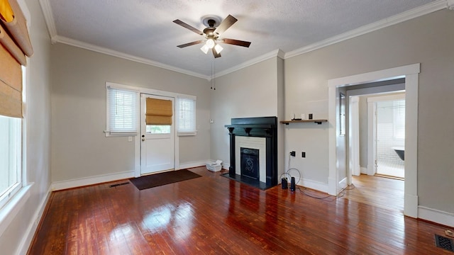 unfurnished living room with a ceiling fan, hardwood / wood-style flooring, a fireplace with flush hearth, ornamental molding, and baseboards
