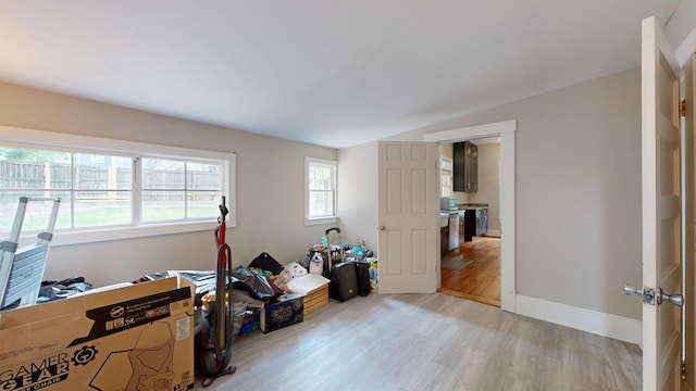 miscellaneous room featuring light wood-type flooring, baseboards, and lofted ceiling