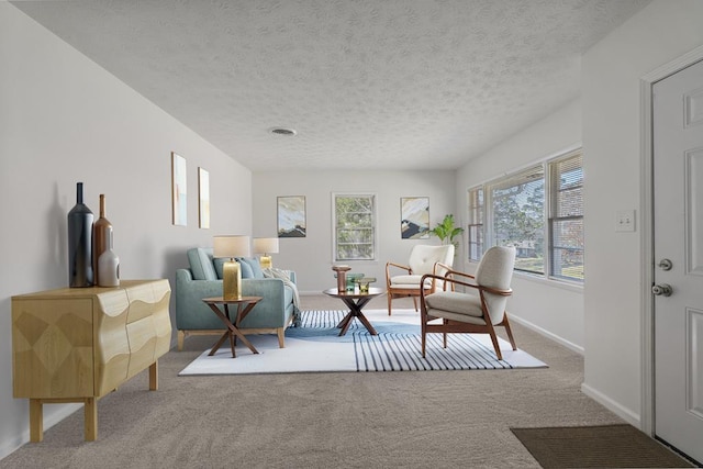 living area with carpet floors, visible vents, a textured ceiling, and baseboards