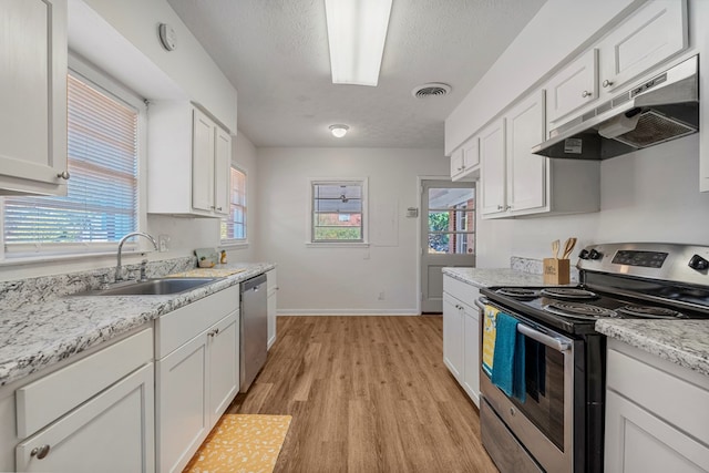 kitchen with stainless steel appliances, visible vents, white cabinetry, a sink, and under cabinet range hood