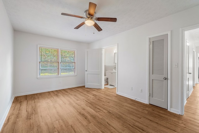 unfurnished bedroom with a textured ceiling, light wood-style flooring, baseboards, a closet, and ensuite bath