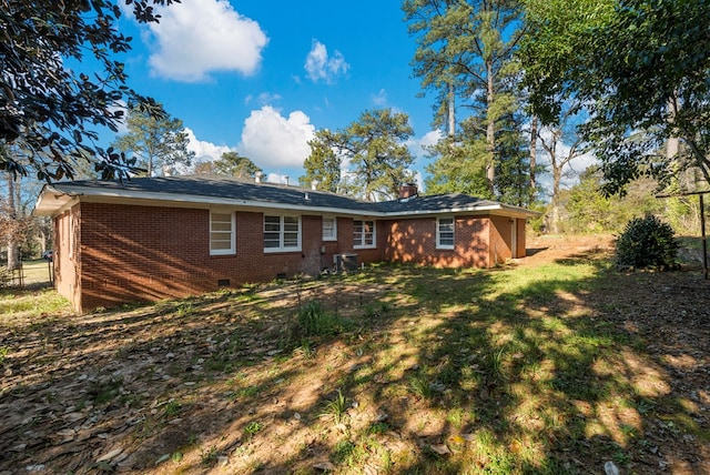 back of property with crawl space, a chimney, a lawn, and brick siding