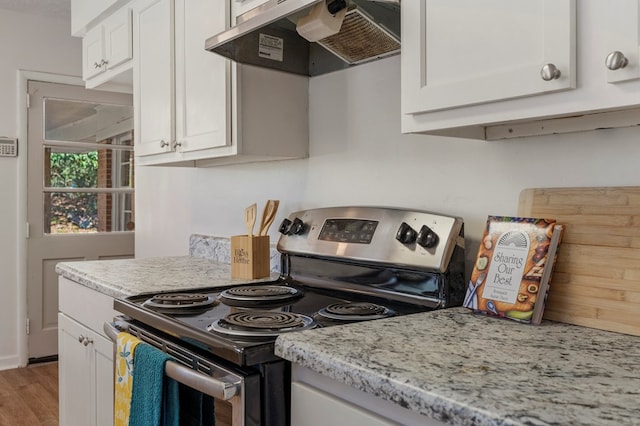 kitchen with light stone counters, white cabinets, wood finished floors, under cabinet range hood, and stainless steel electric range