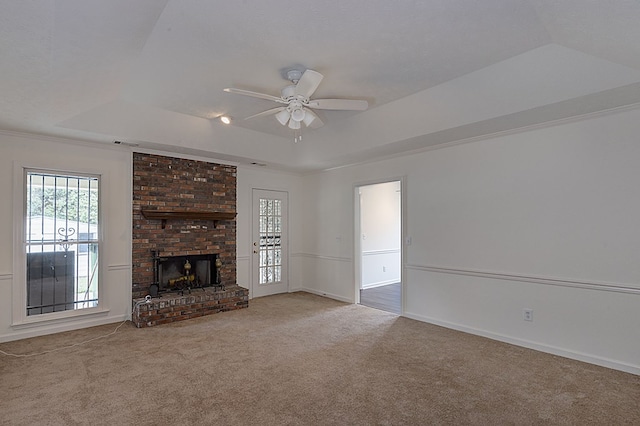 unfurnished living room featuring a tray ceiling, ceiling fan, and light carpet