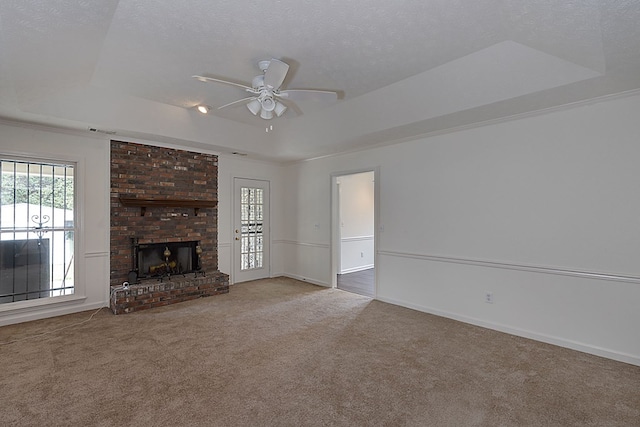 unfurnished living room with a textured ceiling, a raised ceiling, ceiling fan, a fireplace, and carpet floors