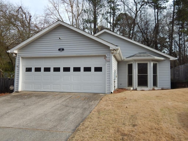 ranch-style house with driveway, an attached garage, fence, and a front yard