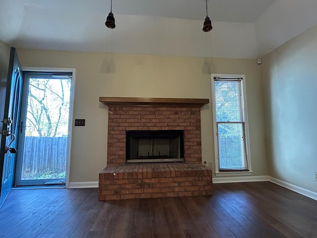 unfurnished living room featuring a brick fireplace, baseboards, and hardwood / wood-style floors